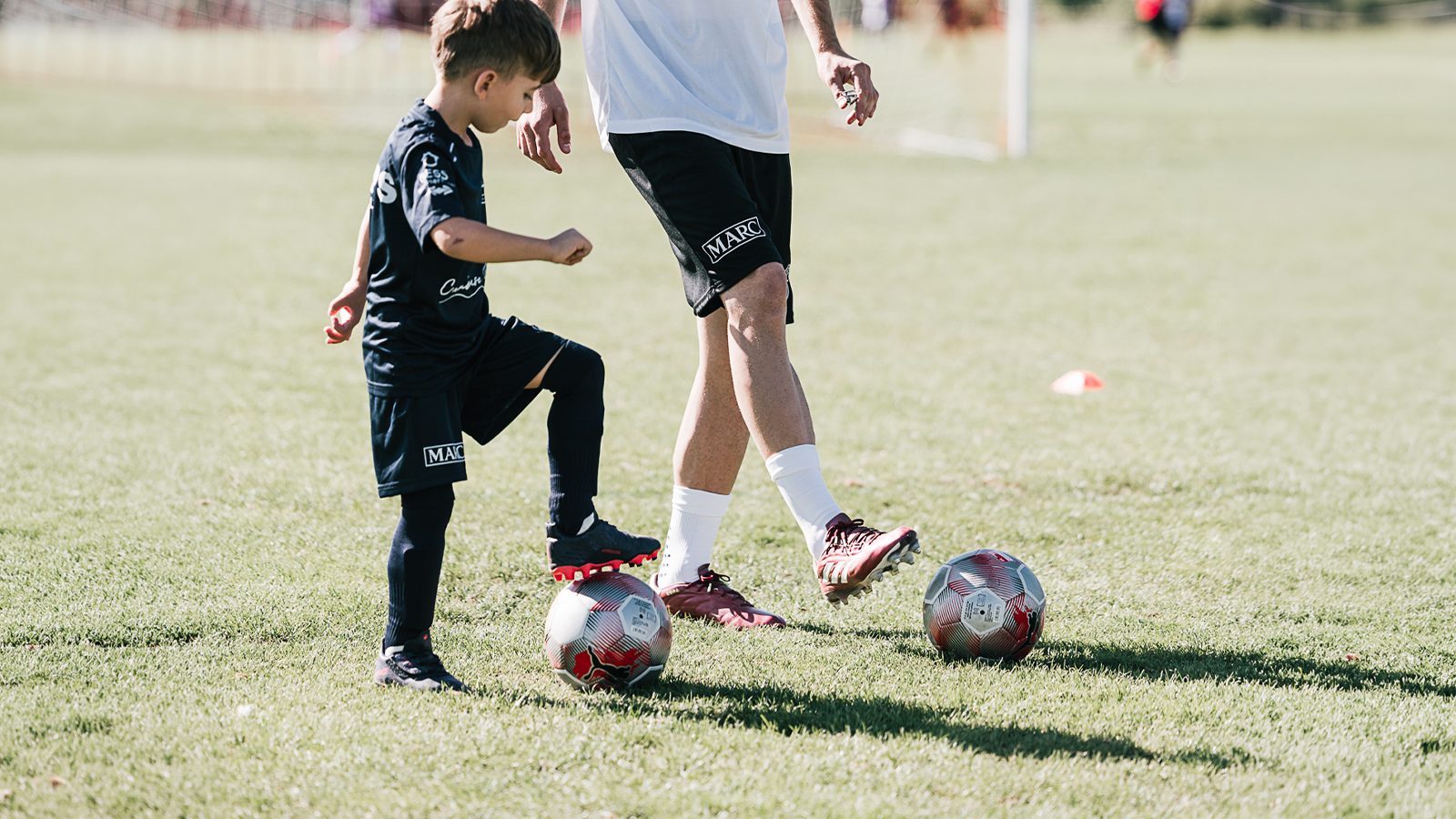 Un coach et un enfant à l'entraînement, ballon au pied